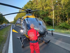Zdjęcie przedstawia: helikopter ratunkowy, przed nim stoi ratownik medyczny.