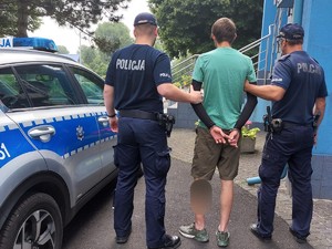 Zdjęcie przedstawia dwóch umundurowanych policjantów z zatrzymanym mężczyzną.