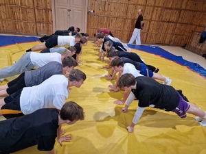 Zdjęcie przedstawia grupę młodzieży, która ćwiczy na macie.