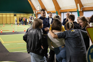 Zdjęcie przedstawia: umundurowanego policjanta podczas rozmowy z grupą młodzieży.
