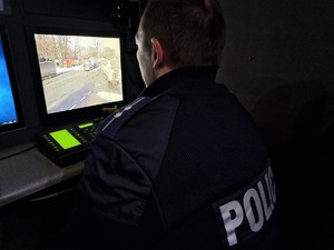 Zdjęcie przedstawia: policjanta przed monitorem komputera.