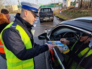Zdjęcie przedstawia: policjanta wręczającego kierowcy gadżety Kolei Śląskich.