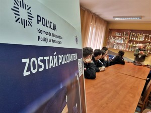 Zdjęcie przedstawia: plakat informujący o rekrutacji w Policji, z tyłu widoczni kadeci podczas zajęć